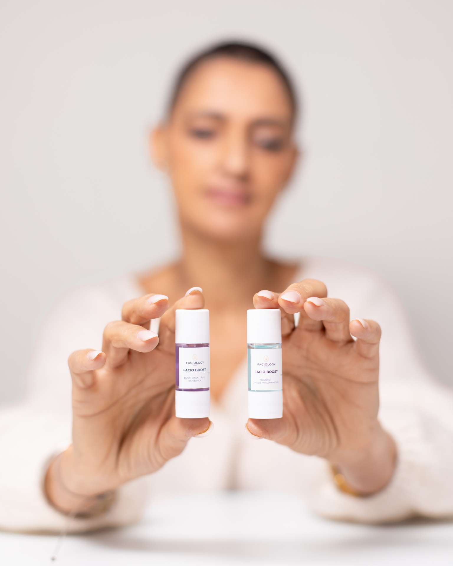 Photo par Antoine Ravet pour la marque Faciology, détail des flacons avec le modèle en arrière-plan.